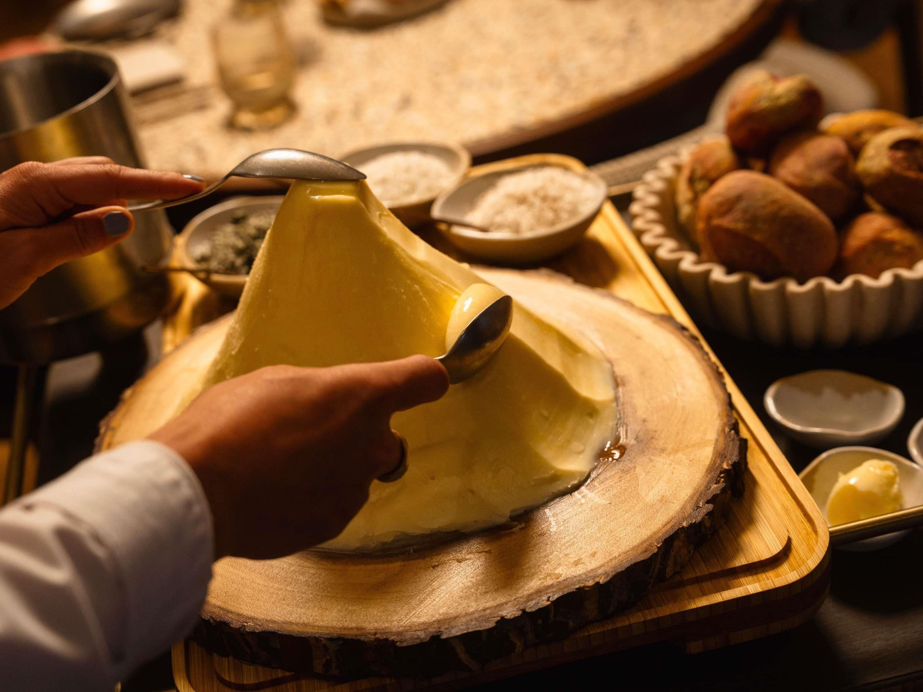 A person scooping a yellow substance from a wooden bowl.