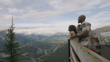 Un belvédère offrant une vue panoramique sur les montagnes, doté d’une rambarde en bois et d’un panneau indiquant le lieu.