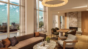 A modern living room with a large window, a fireplace, and a dining area. - Rimrock Banff, Emblems Collection (Banff)