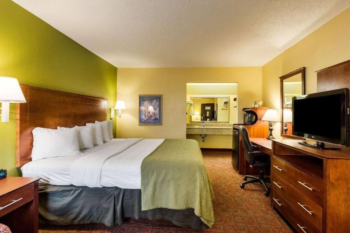 Une chambre d’hôtel équipée d’un lit, d’un bureau, d’une télévision et d’un miroir.
