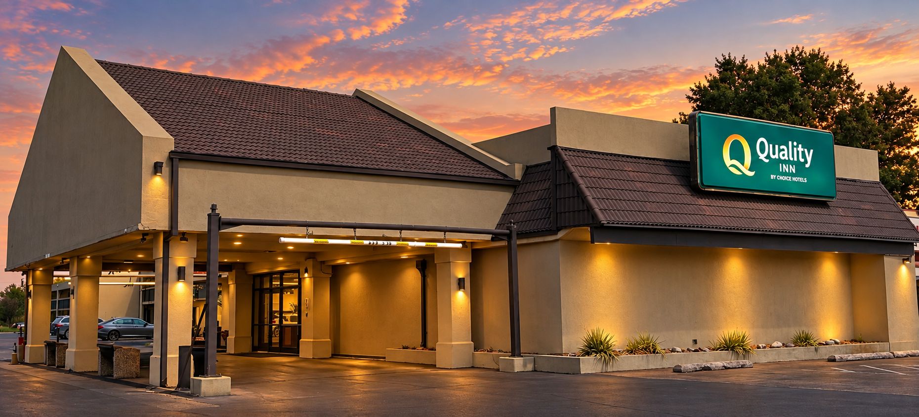 A hotel with a sign reading 'Quality Inn by Choice Hotels,' featuring a modern design with a flat roof and a covered entrance.
