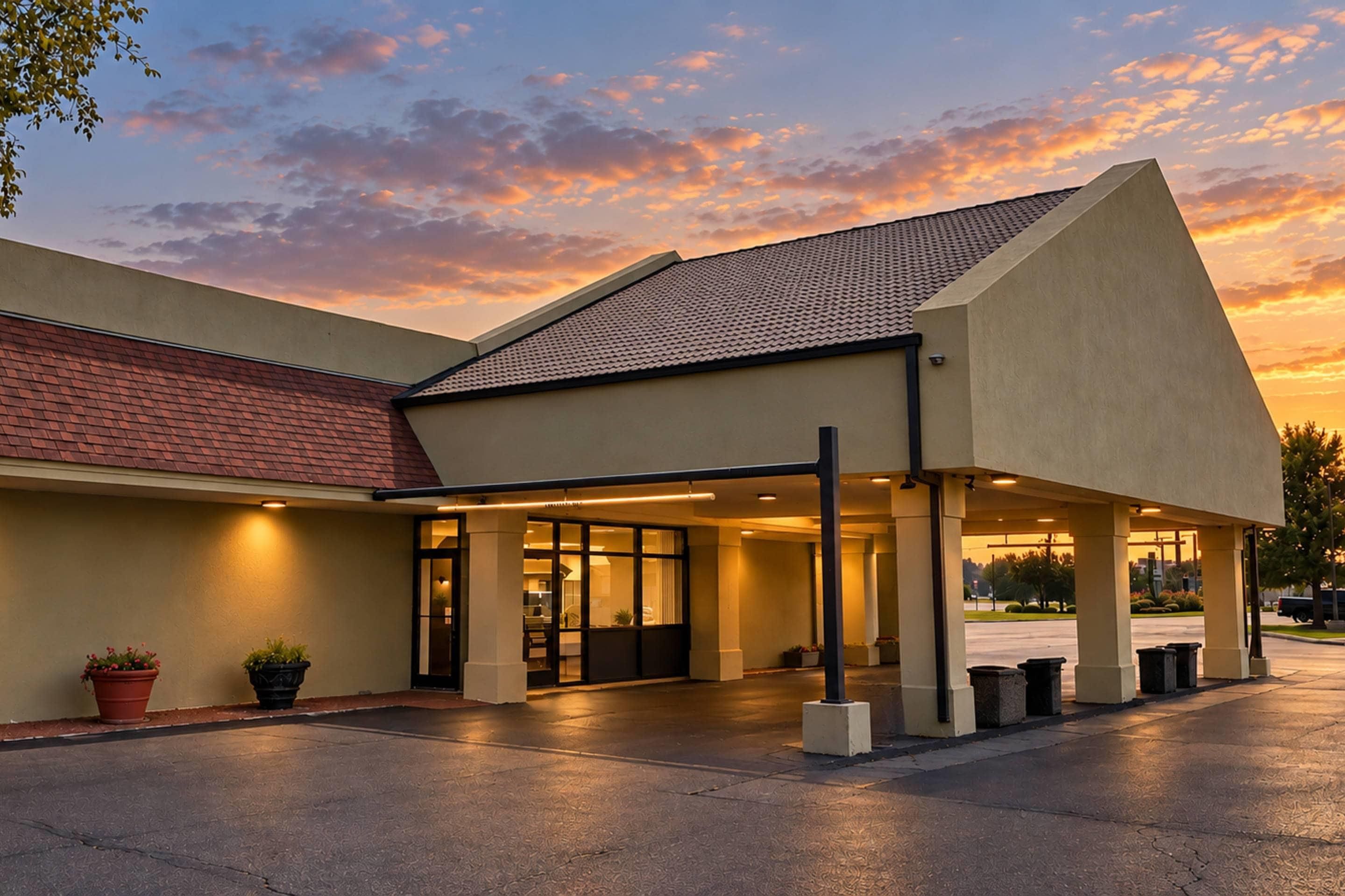 Un hotel con entrada cubierta, techo de tejas y zona de estacionamiento.
