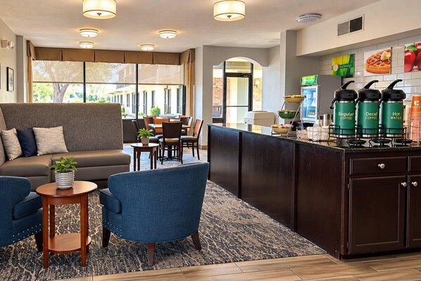 A hotel lobby with a seating area, a bar, and a kitchenette.