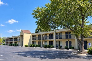 Ein Motel mit Parkplatz und einem Baum im Vordergrund.