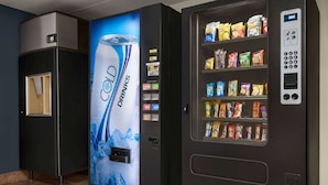 A vending machine with a Coca-Cola advertisement and a selection of snacks. - Days Inn by Wyndham Fort Collins (Fort Collins)