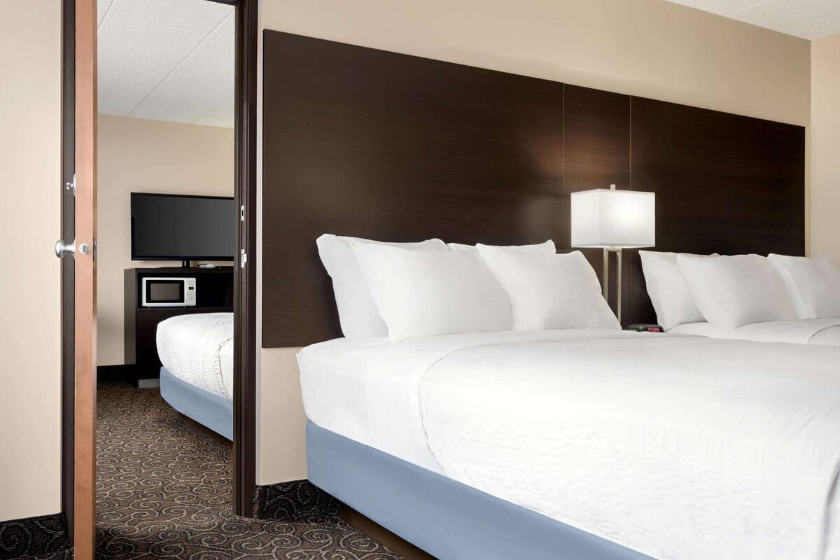 A hotel room with a large bed, a television, a microwave, and a bedside lamp.