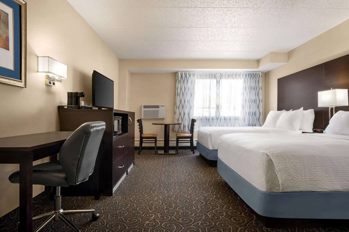 A hotel room with a bed, a desk, a chair, a television, and a window with curtains.