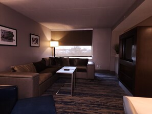A living room with a sofa, a coffee table, a lamp, and a large window.