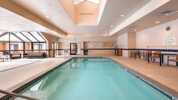 A swimming pool with a sunroof, seating area, and a warning sign.