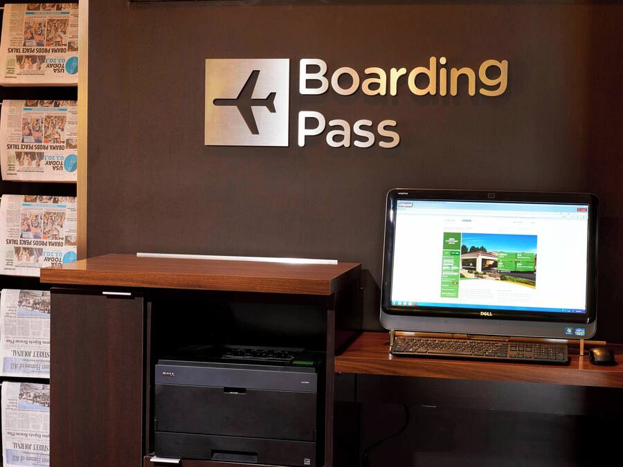 Een bureau met een computer waarop een boardingpas, een printer en een muur met een bord dat 'Boardingpas' zegt.