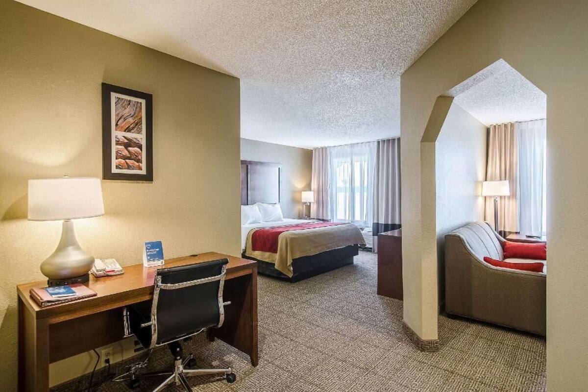 A hotel room with a desk, chair, bed, and a sofa.