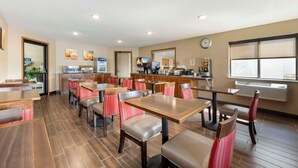 A restaurant with wooden tables and chairs, a kitchen area, and a clock on the wall. - Comfort Inn Lexington (Lexington)
