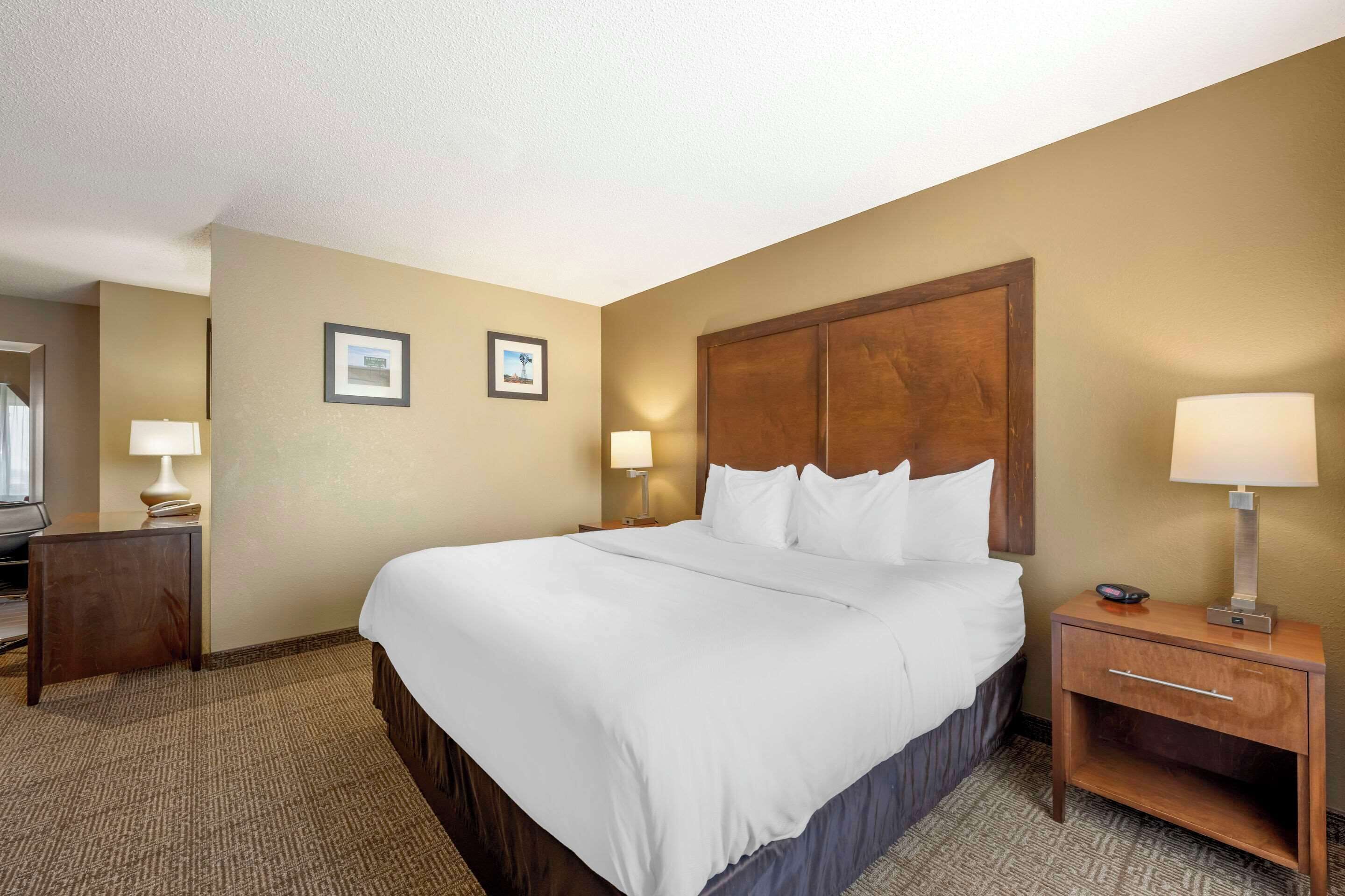 A hotel room with a large bed, two bedside tables with lamps, and a television on a stand.