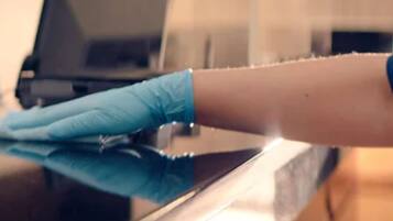 A close-up of a hand wearing a blue glove cleaning a reflective surface.