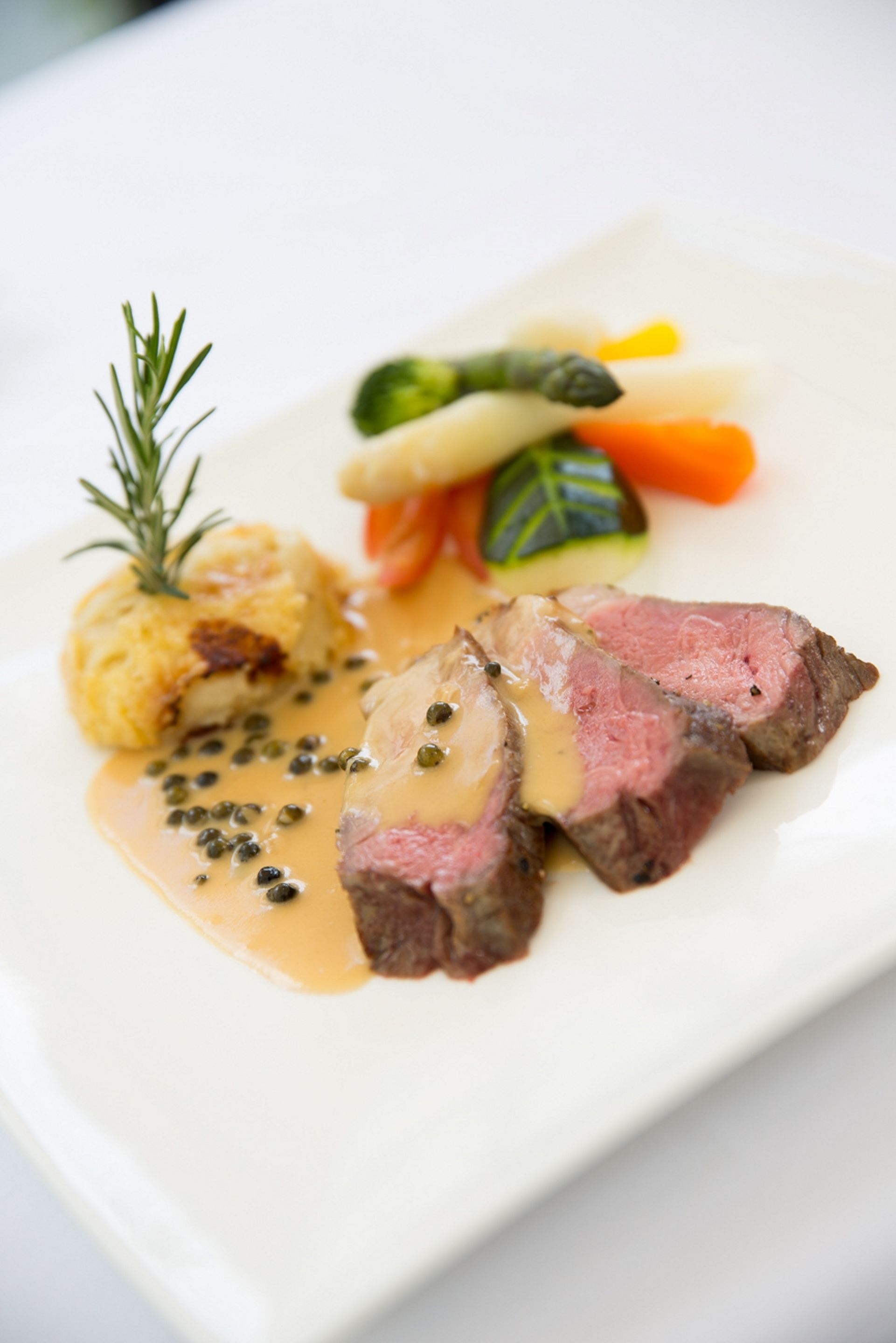 A plate of food with a steak, vegetables, and dumplings.