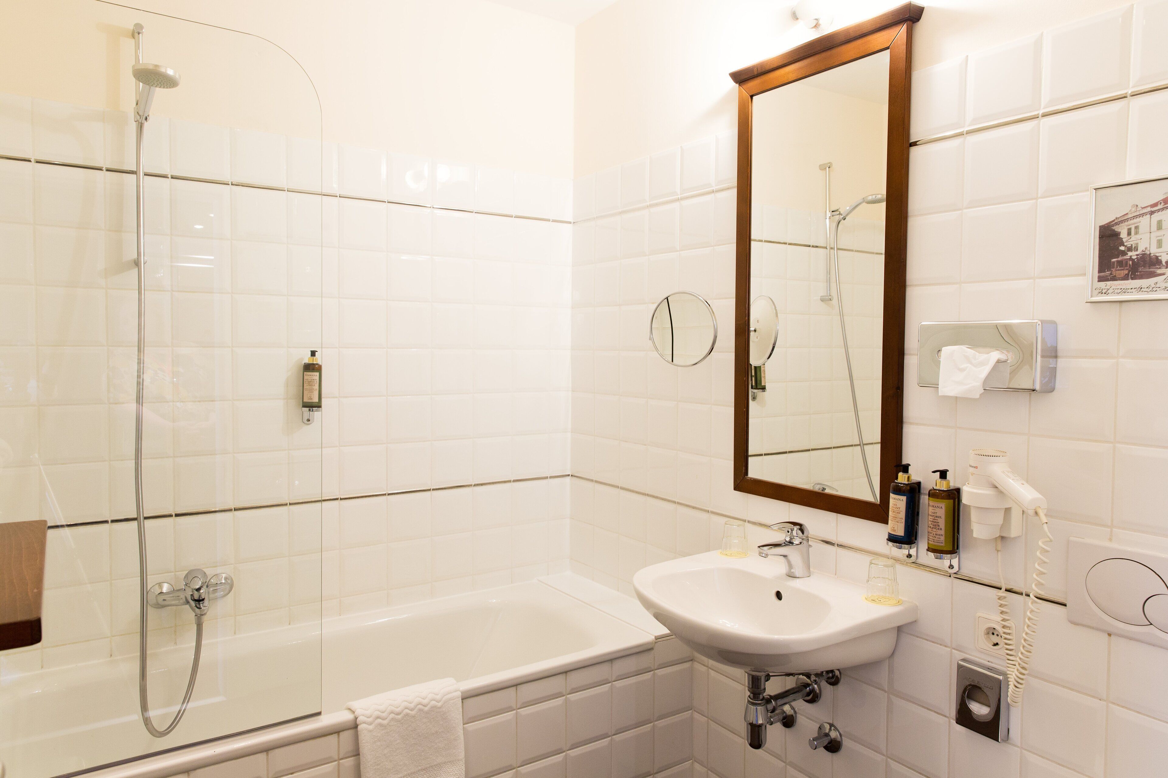 Une salle de bain avec une douche à parois de verre, un lavabo blanc et un grand miroir.