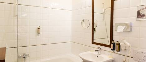 Une salle de bain avec une douche à parois de verre, un lavabo blanc et un grand miroir.