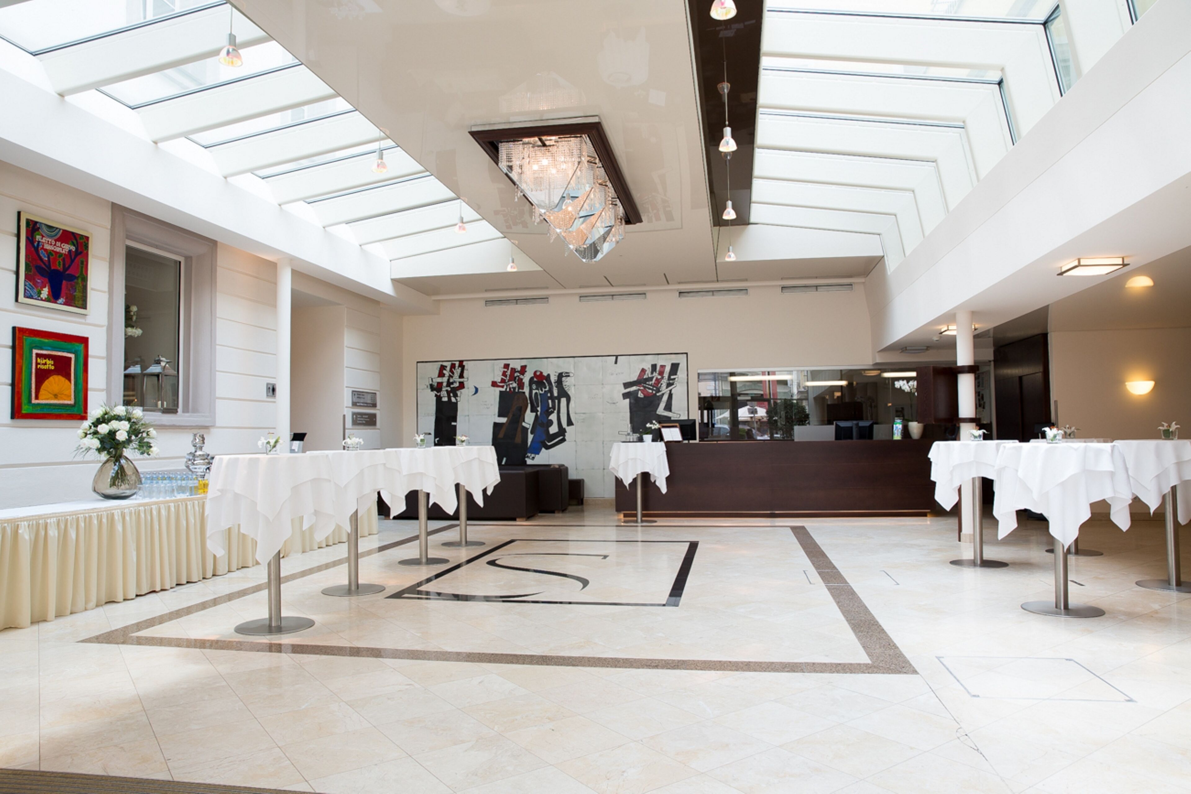 A spacious lobby with high ceilings, a central chandelier, and a reception desk.