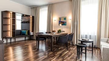 Ein modernes Wohnzimmer mit Essbereich, Holzböden, integrierten Regalen und einem großen Fenster mit Vorhängen.