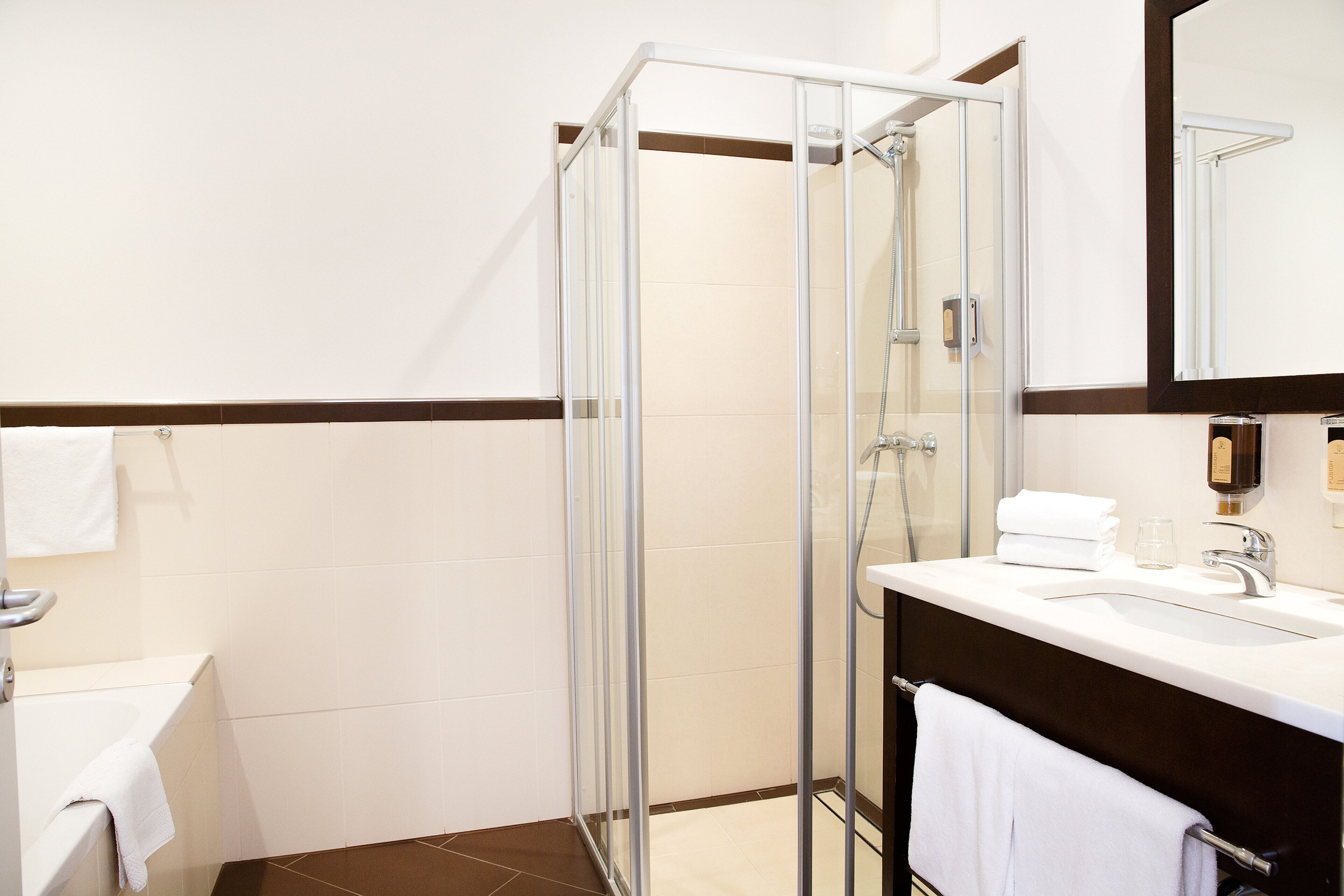A modern bathroom with a glass-enclosed shower, a white sink, and a dark-toned vanity.