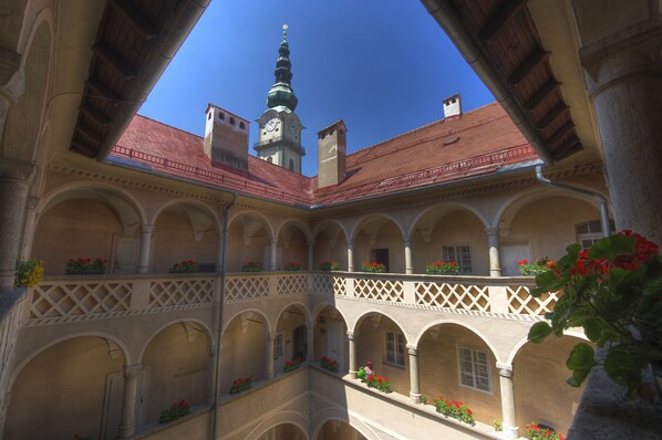 Un patio con varios arcos y balcones, algunos con jardineras.