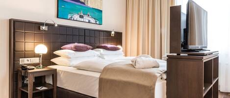 Een hotelkamer met een bed, een nachtkastje met een lamp, een televisie en een schilderij aan de muur.