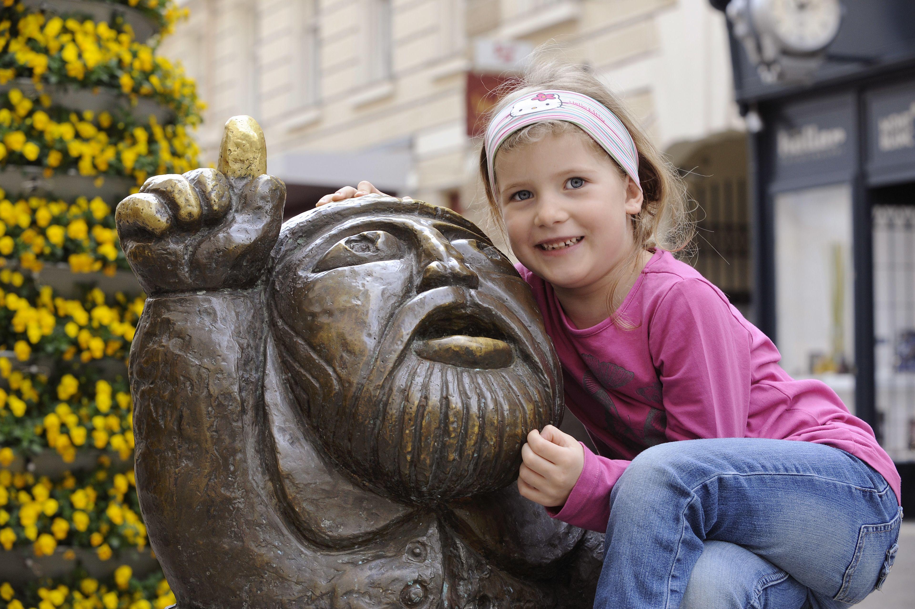 A child interacting with a bronze sculpture of a man's face.