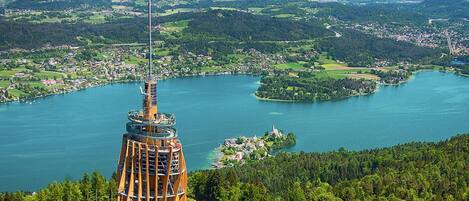 A panoramic view of a lake surrounded by lush greenery and a distinctive tower structure.
