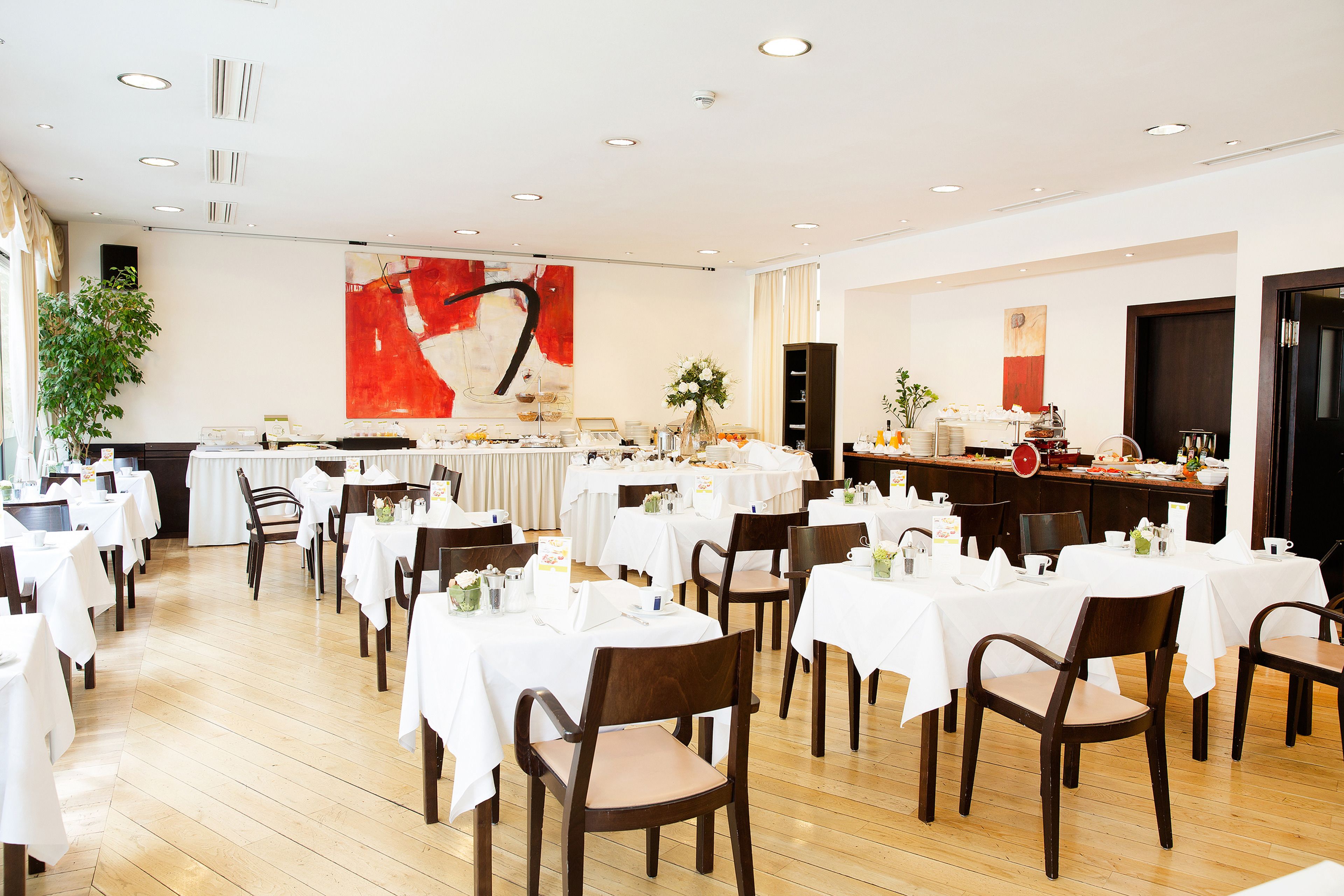 Un comedor con mesas redondas, sillas y una barra de buffet.