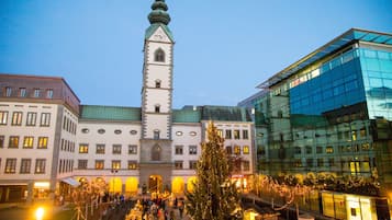 Un edificio histórico con una torre de reloj, rodeado de arquitectura moderna y un área de mercado festiva.