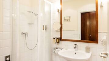 A modern bathroom with a glass-enclosed shower, a white sink, and a wooden-framed mirror.