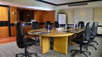 A conference room with a large oval table, black leather chairs, and a whiteboard.
