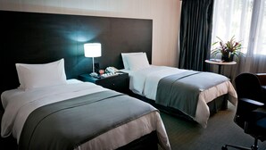 A hotel room with two beds, a bedside table with a lamp, a small table with a plant, and a chair. - Hotel Tamanaco Caracas (Caracas)