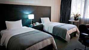 A hotel room with two beds, a bedside table with a lamp, a small table with a plant, and a chair. - Hotel Tamanaco Caracas (Caracas)