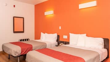 Ett hotellrum med två sängar, var och en med ett rött och beige täcke, vita kuddar och ett nattduksbord med en telefon.