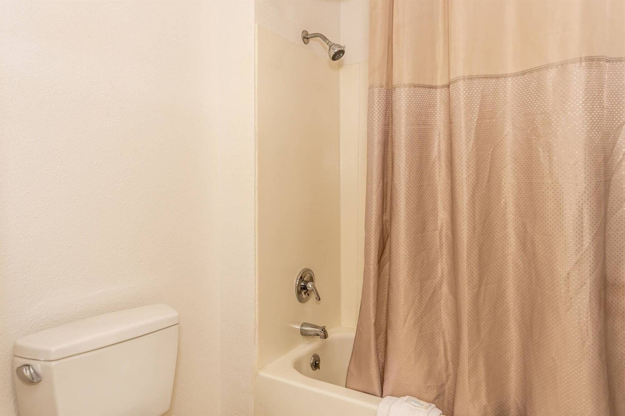 Een badkamer met toilet, bad en douchegordijn.