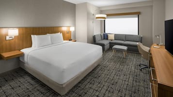 A hotel room with a large bed, a sofa, a desk, and a TV.