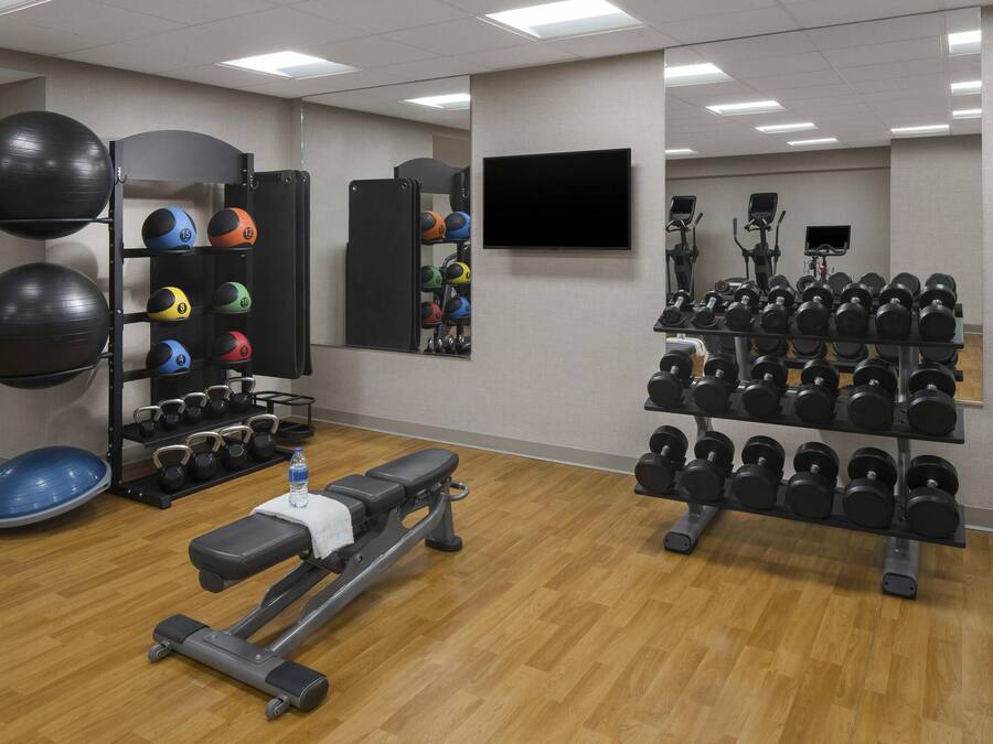 A gym with exercise equipment, including a bench, weights, and a treadmill.