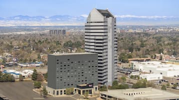 A modern hotel with a central courtyard, surrounded by other buildings, with a mountain range in the background.