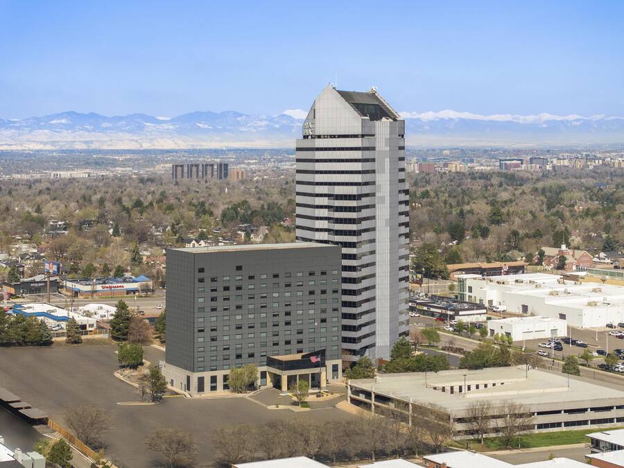 A modern hotel with a central courtyard, surrounded by other buildings, with a mountain range in the background.