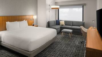 Una habitación de hotel con una cama grande, un sofá, un escritorio y un televisor.
