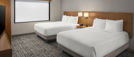 A hotel room with two beds, a television, and a window with a view.