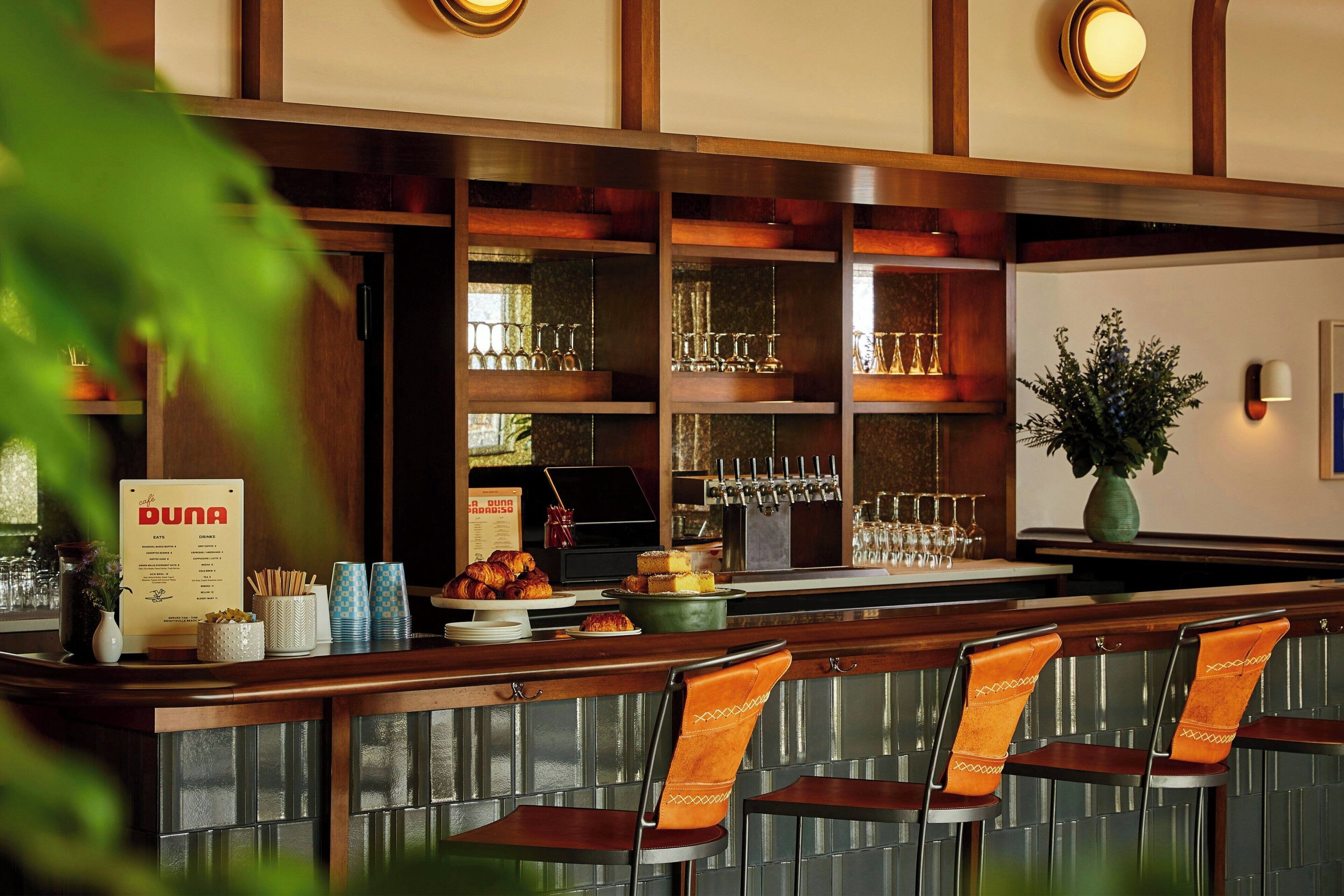 A bar area with a menu board, glasses, and a selection of pastries.