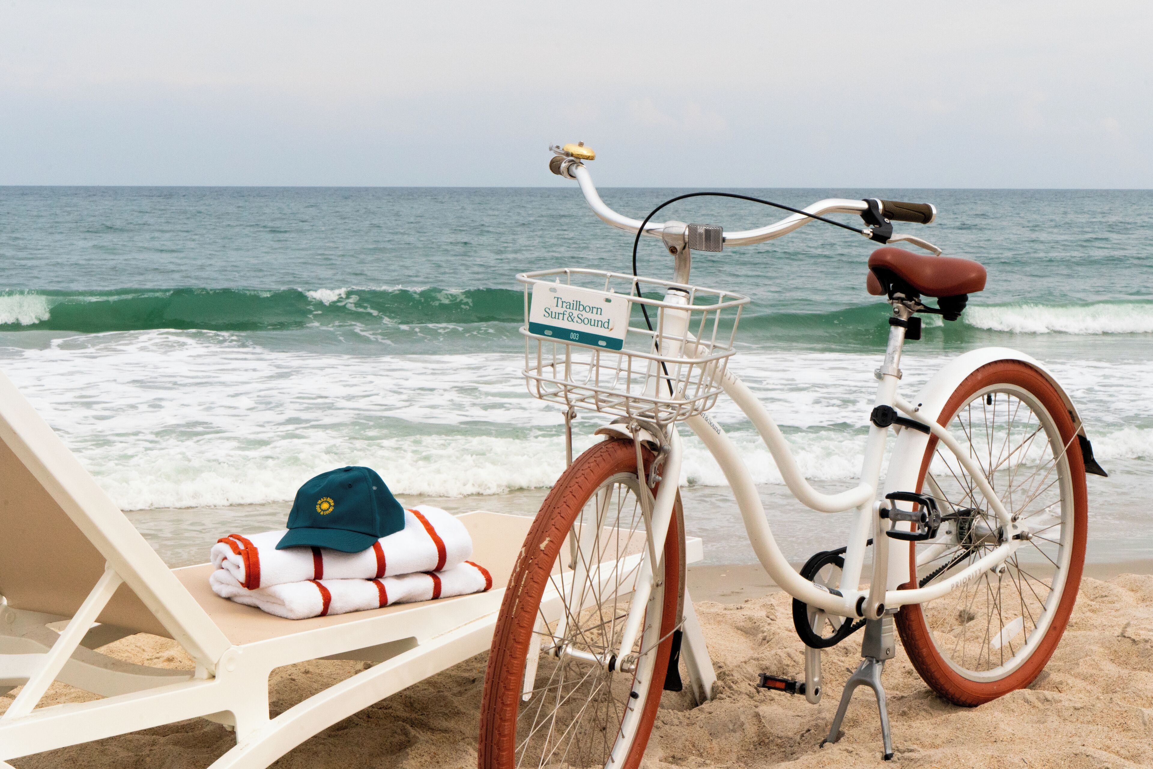 Eine Strandansicht mit einem Fahrrad und einem Liegestuhl.
