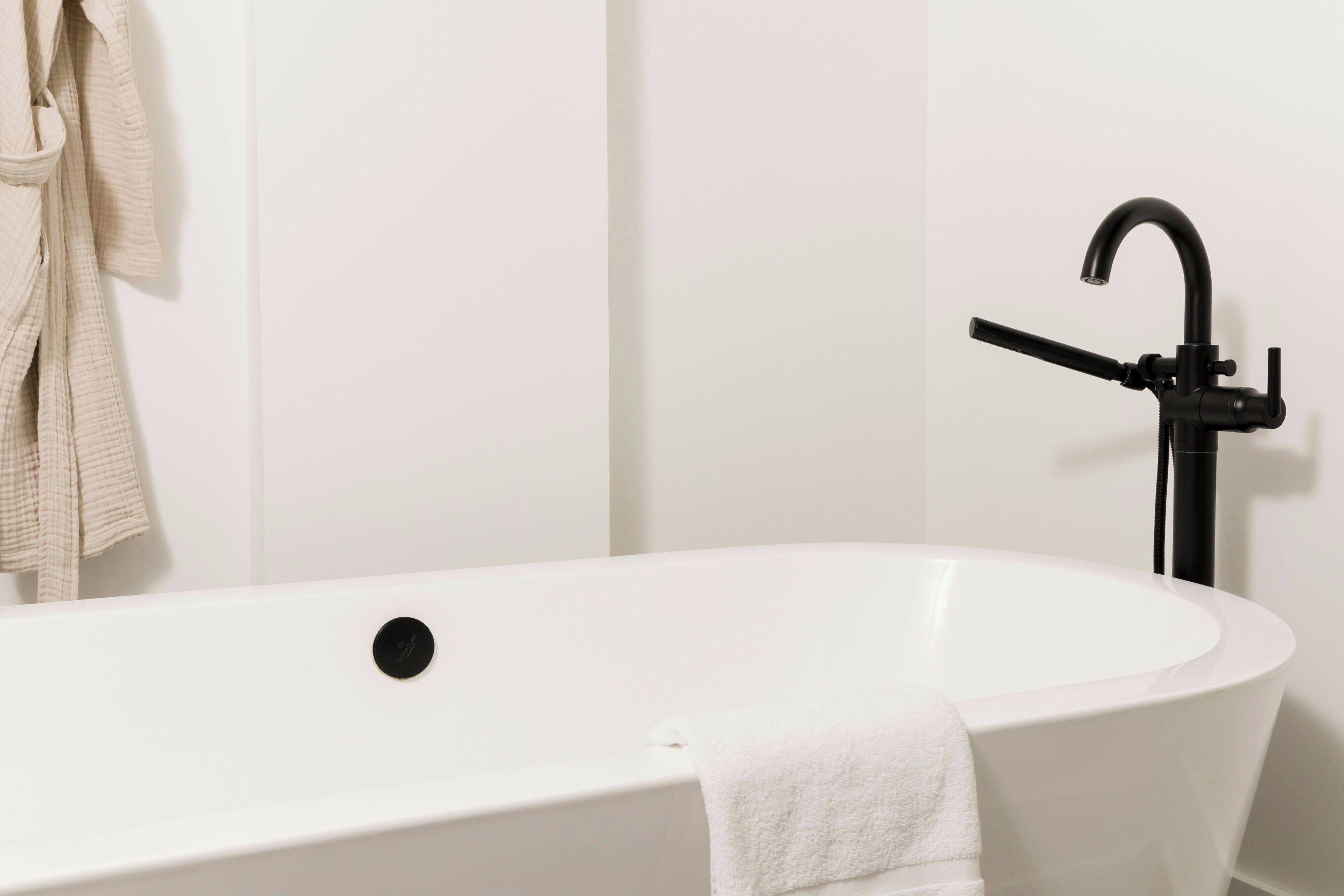 Une salle de bain moderne avec une baignoire sur pieds, une serviette et un robinet noir.