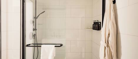A modern shower area with a glass door, a towel rack, and a visible showerhead.