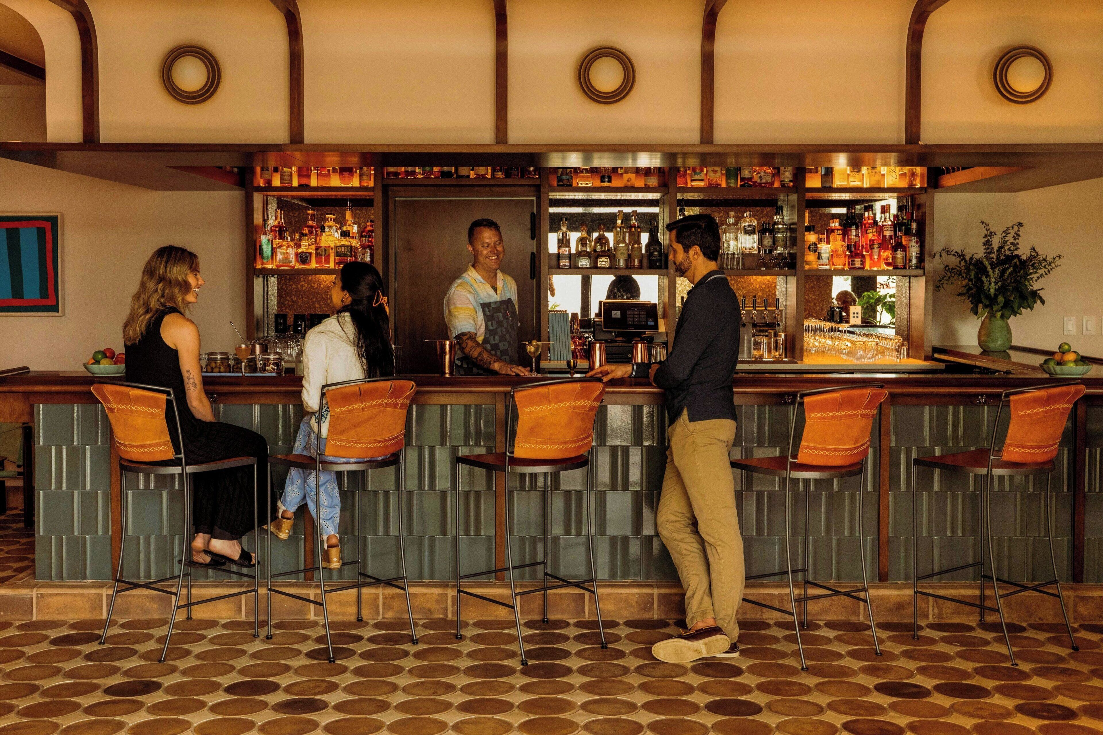 A bar area with a counter, stools, and a bartender.