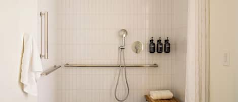 A shower with a handheld showerhead, a towel rack, and a shelf with toiletries.