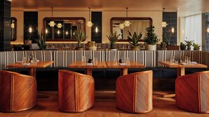 Un restaurant avec des banquettes à rayures, des tables en bois et des chaises en osier.
