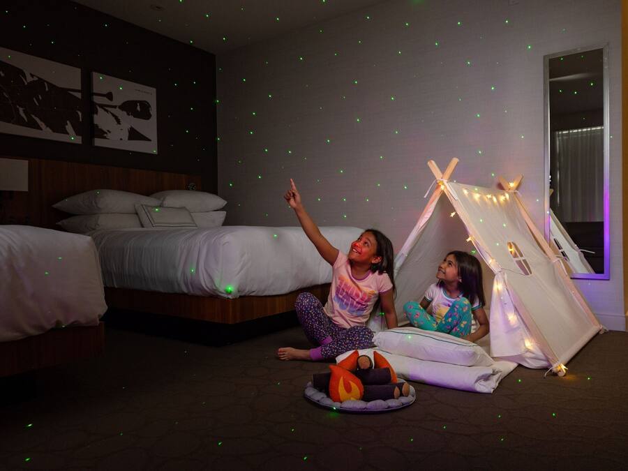 Un dormitorio con cama, tienda de campaña y un techo que simula un cielo estrellado.